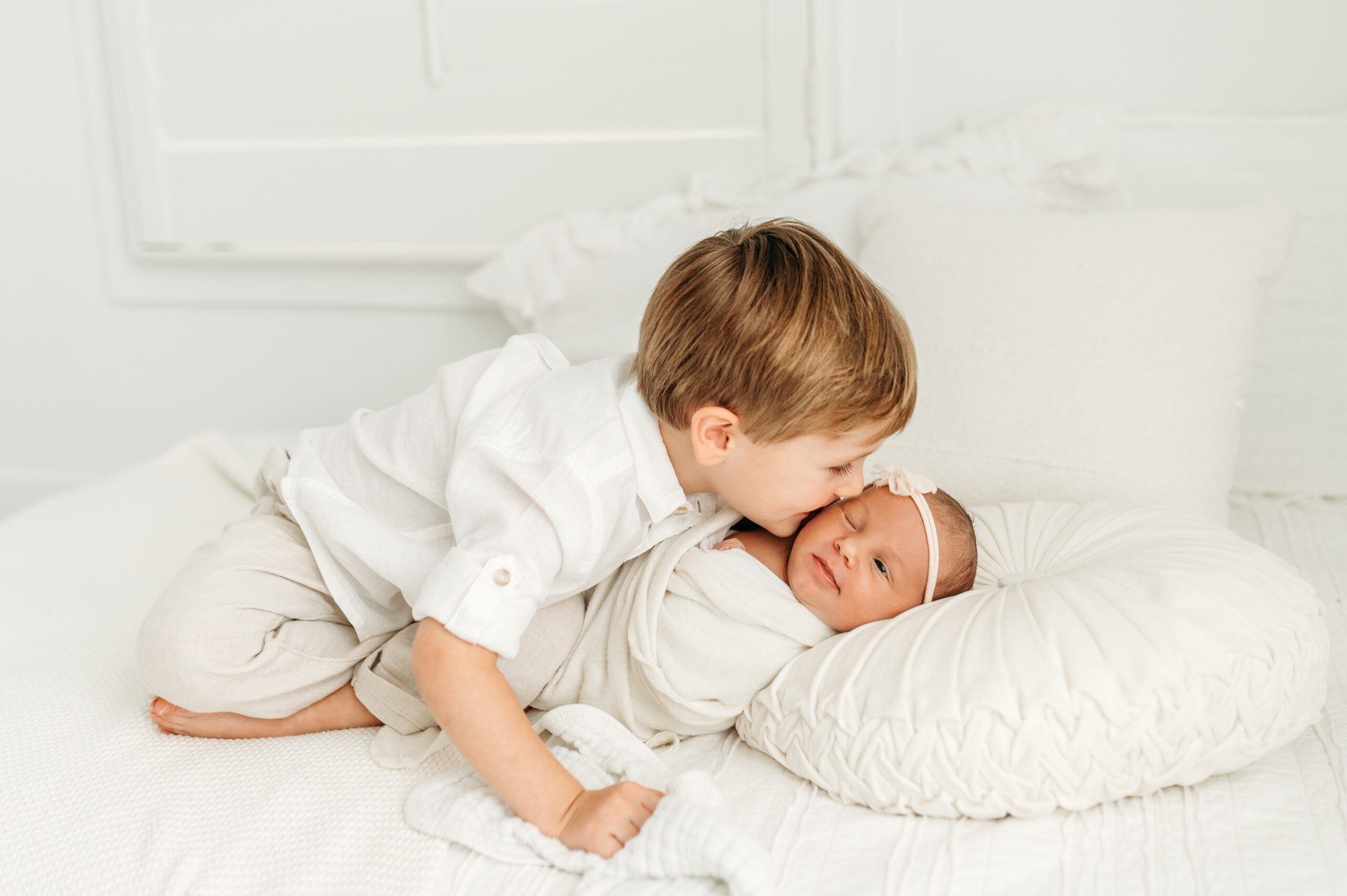 Big brother is kissing his new baby sister on the cheek during their Atlanta Newborn session.