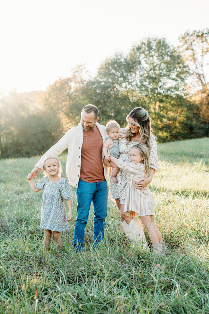 The family session in Birmingham Park, Atlanta, is at sunset, and all family members are laughing and enjoying each other.