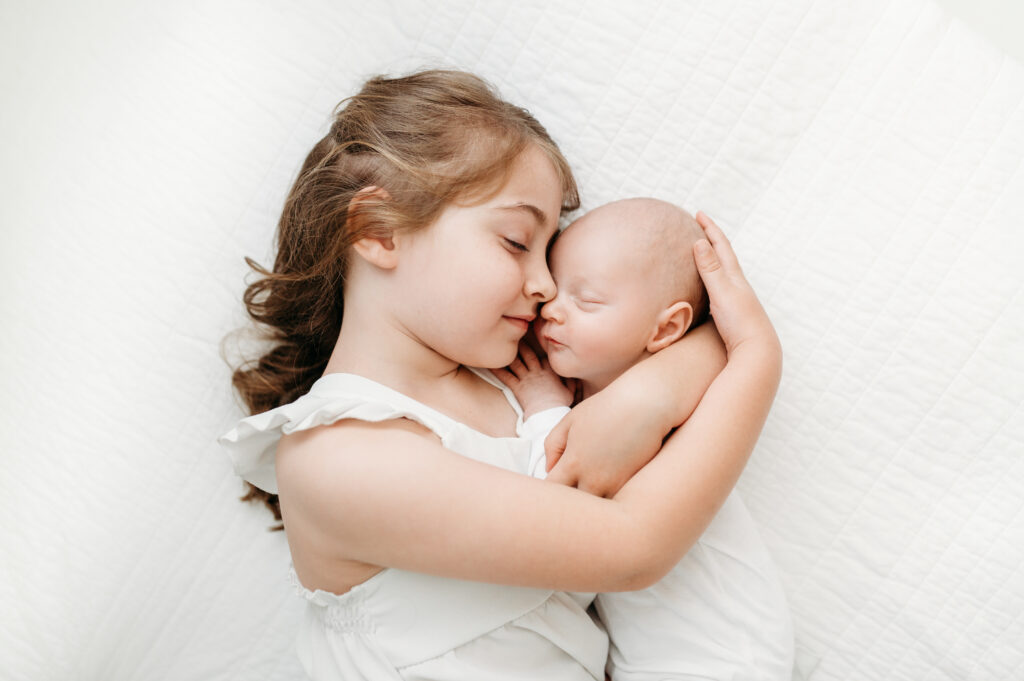 sweet sister holding her baby brother during newborn photos